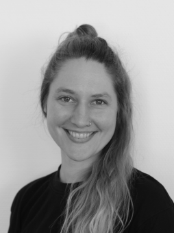 Schwarzweißes Portrait von Lea Valentin. Weibliche, lächelnde Person mit langen, blonden Haaren.